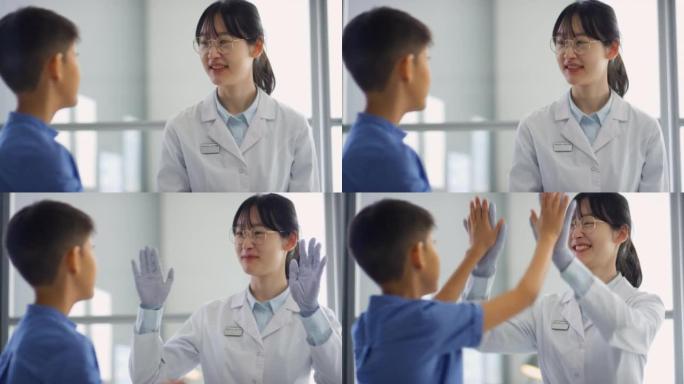 亚洲女医生和男孩在诊所里击掌