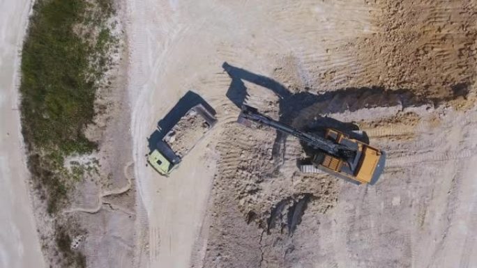 现代挖掘机在采石场上铲高岭土。装载卡车离开工厂。