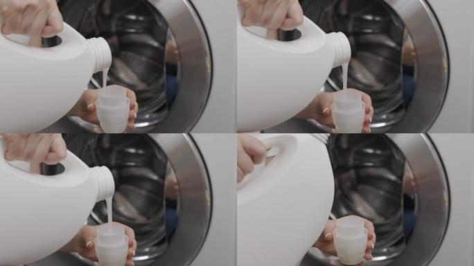 在钢色洗衣机滚筒的背景下，女人将液体洗涤凝胶倒入塑料盖中。一个穿着白色t恤的女孩小心地倒入透明的护发