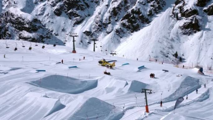 救援直升机降落在斜坡上，帮助滑雪公园的滑雪者。