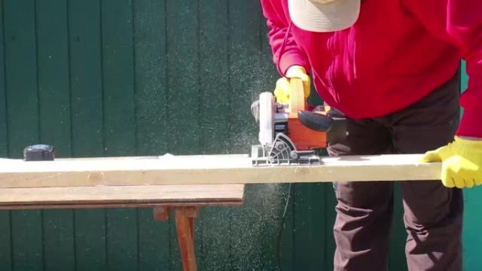 一个人与一棵树一起工作。锯子切了木板。房屋的框架结构。木材加工