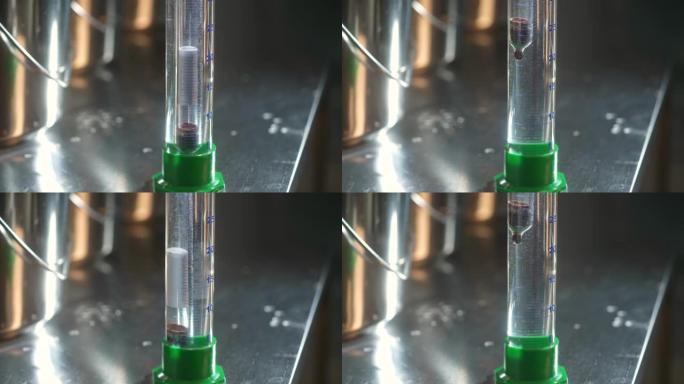 伽利略温度计根据密度的物理学显示温度变化。柠檬水生产。温度计下降到液体中，以检查糖水平