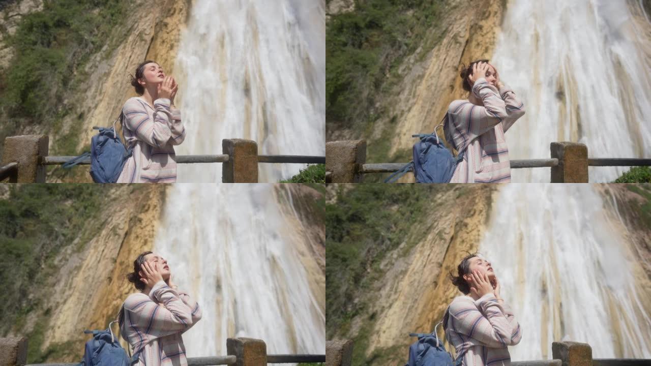 女人站在墨西哥恰帕斯州的El Chiflon瀑布附近，用水滴洗脸