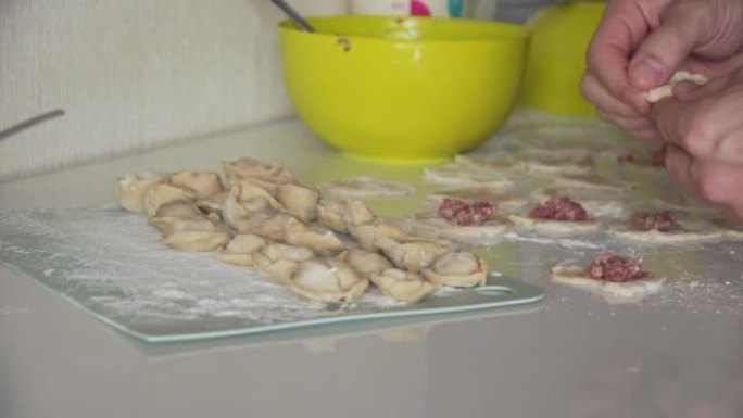 特写女性双手用肉末包饺子。女厨师快速熟练地包饺子，在家做猪肉肉饺。传统俄罗斯美食。