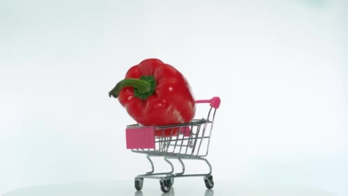 超市手推车里的天然蔬菜甜椒在旋转的桌子上旋转，开胃的红辣椒在白色背景的桌子上旋转