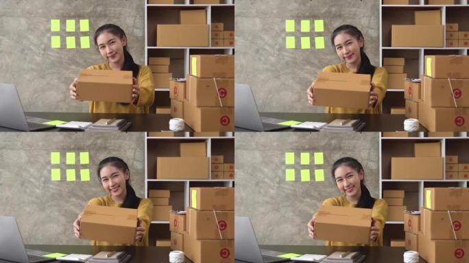 年轻的亚洲女性展示包装盒，自由女性卖家检查产品订单。包装货物以交付给客户。