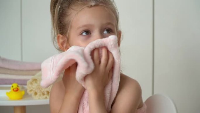 小女孩用毛巾布擦湿脸。洗澡后的孩子。婴儿护理。