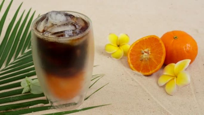 海滩上双层玻璃中的冰咖啡橙汁。