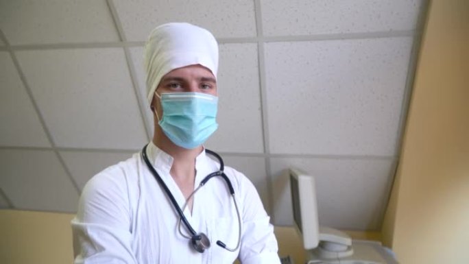 戴着口罩的听诊器的医生看着相机。背景上有超声设备的医院