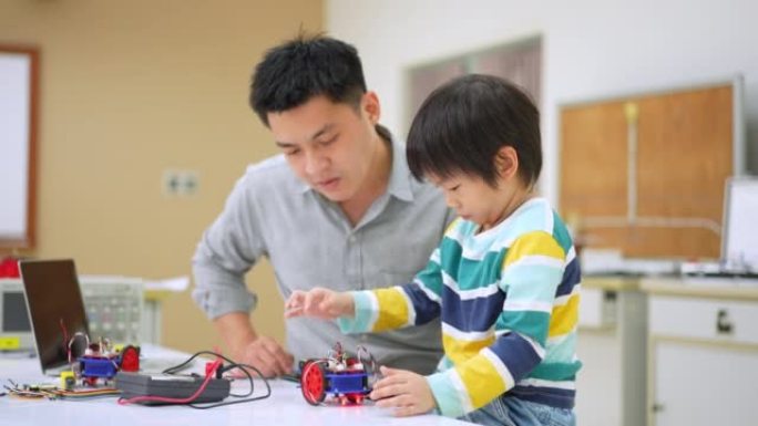 亚洲学生和老师使用电子仪表和笔记本电脑在科学课中构建自主自驱动机器人汽车的原型