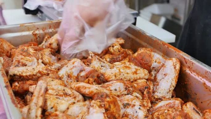 市场上的肉贩从容器中取出腌制过的鸡翅，然后用秤称给顾客。腌好的生辣鸡翅
