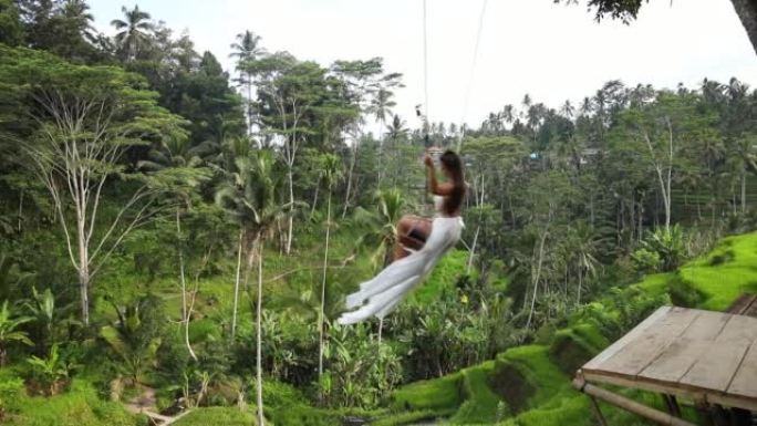 穿着婚纱的女人在巴厘岛的水稻梯田上摇摆着美丽的景色