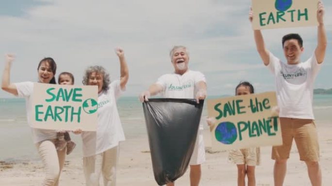 快乐的亚洲大家庭穿着志愿者衬衫培养孩子学习如何在海滩上保护自然。大家庭拿着纸板进行运动，以拯救地球免