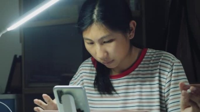 亚洲女孩在家里的餐桌上做作业时使用数字平板电脑和铅笔，生活方式理念。