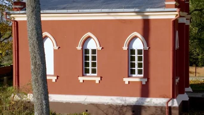 外部，带有ahite拱形窗户的小教堂的橙色墙壁