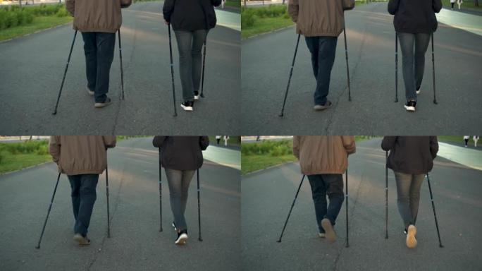 一对老年夫妇在公园里从事北欧散步。一个男人和一个女人用棍子走路来改善健康。