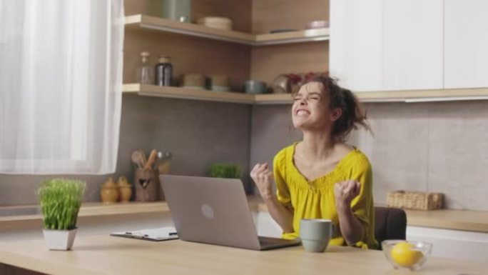 快乐的女人在笔记本电脑上阅读好消息时打手势