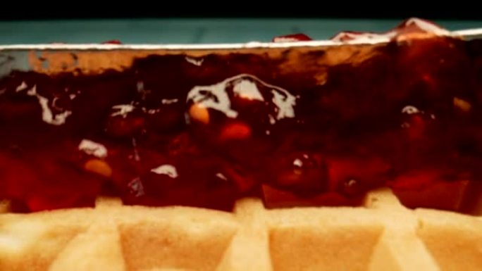 宏观: 覆盆子果酱用小刀铺在木桌上的华夫饼上