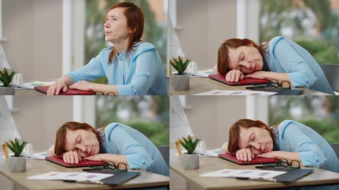 侧视图疲惫的成熟女人坐在办公室的桌子旁叹息着小睡。悲伤疲惫的高加索女商人把头放在桌子上闭上眼睛的肖像