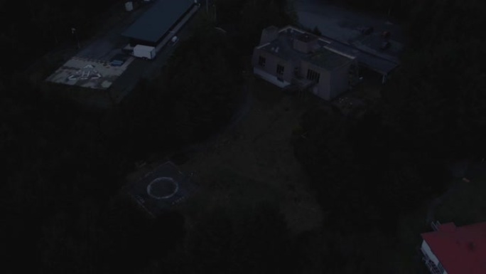 无人机在黑暗中被树木包围的建筑物上的视野