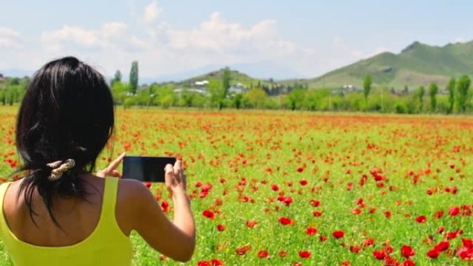 年轻的高加索女性在佐治亚州户外用手机拍照美丽的盛开的山罂粟花