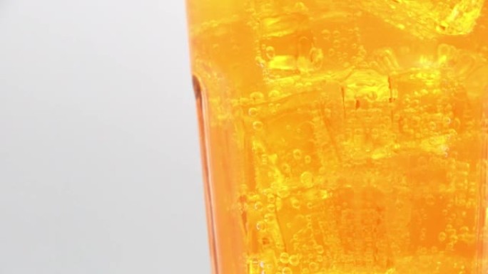 在白色背景上旋转一杯橙色苏打水饮料。