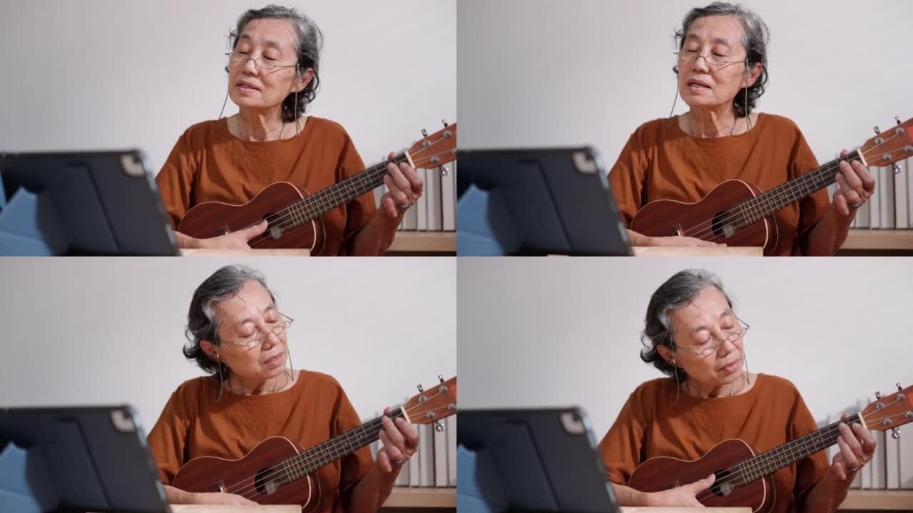 退休的高级女性坐在客厅里，在家中使用笔记本电脑在线学习吉他