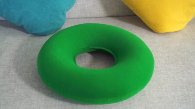 沙发上的圆形绿色矫形枕头特写，痔疮的概念