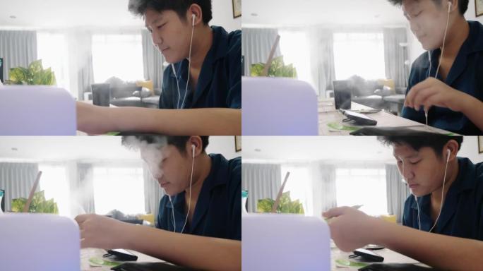 亚洲男孩在家用蒸喷机附近的餐桌学习在线课程，社交疏远的生活方式理念。