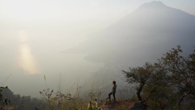 日落时分，男子站在危地马拉阿蒂特兰湖背景上的山上