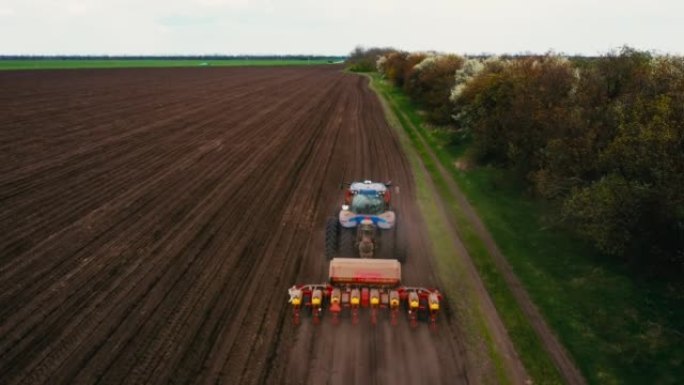 农民在拖拉机上，用播种机械在田间播种小麦或玉米。农艺农场的工作概念，以生产有机食品并从中获利