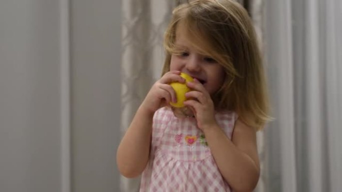 穿着可爱的女婴的肖像，坐在室内高脚椅上吃酸柠檬。高质量4k镜头
