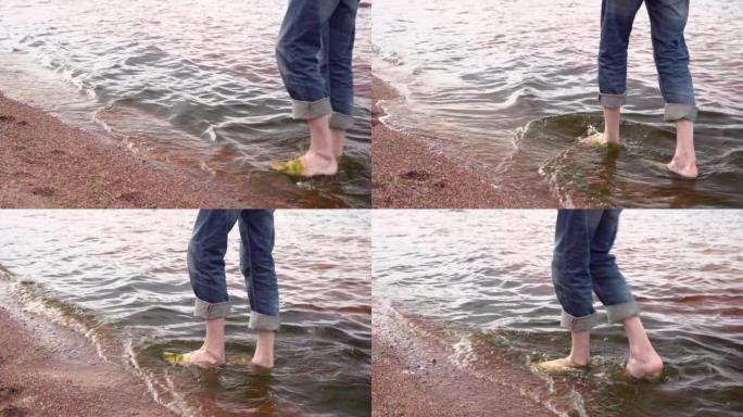 穿着蓝色卷起牛仔裤的瘦子的腿在水上行走
