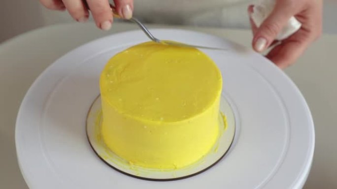 糖果用烹饪刮铲特写在蛋糕上放黄色奶油
