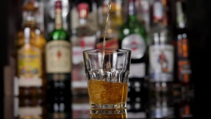 酒保将威士忌倒入酒吧的玻璃杯中，一名男子拒绝喝酒。