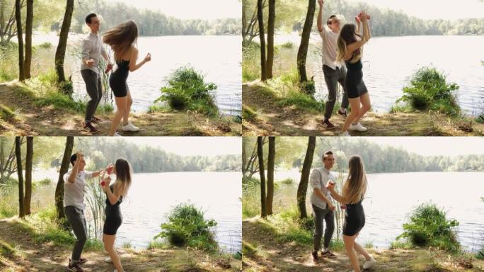 快乐的年轻人夫妇在湖岸乡村大自然中跳舞，约会时心情愉快