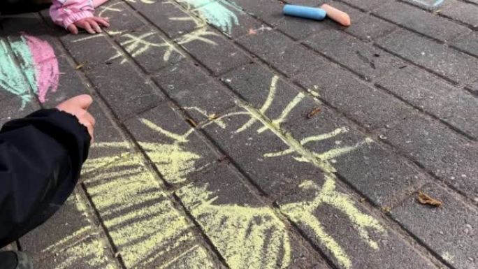 小孩在沥青上用粉笔画太阳
