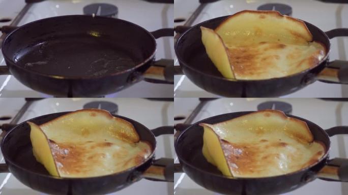 在黑色煎锅中烹饪煎饼的过程，在油炸过程中，用硅胶刮刀将煎饼翻转