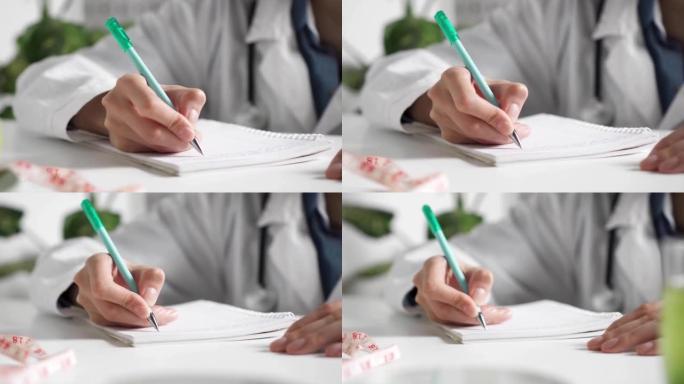 手在日记里写。记录患者信息。一位女医生坐在医疗机构的桌子旁