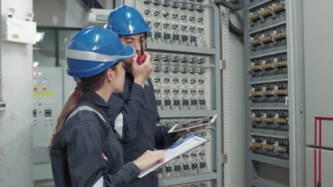 一名电工工程师在工业工厂操作台网络控制室工作，检查和记录电气保护继电器参数。