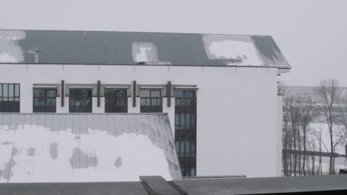 现代立面建筑的冬季景观，屋顶上有雪。暴风雪在吹。
