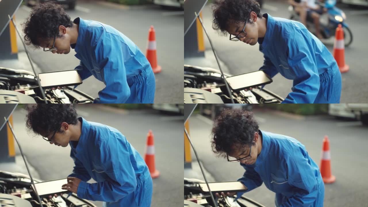 穿着蓝色连身衣的亚洲中年汽车修理工使用数字平板电脑进行车辆检查证书，家庭服务