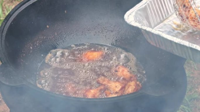 在木头上的油炸大锅中炸鸡翅