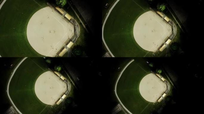 晚上棒球场的空中无人机镜头，人们在草地上打棒球。最佳镜头