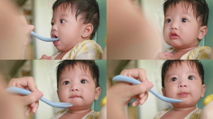 可爱的亚洲宝宝在椅子上吃婴儿食品。