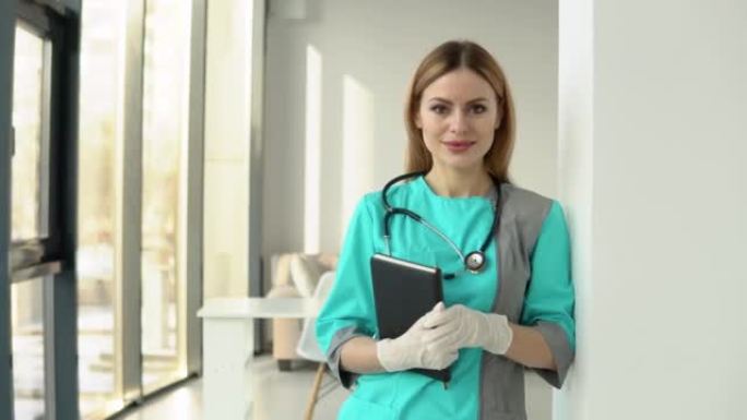 一名身穿医大衣、手持听诊器、手持文件的女医生看着镜头。医院办公室微笑的女医生或护士