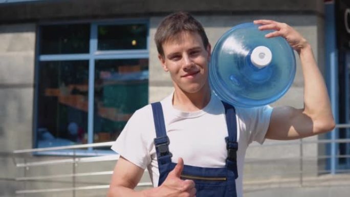 Courier在玻璃现代高层建筑的背景下，肩上扛着一大罐饮用水。送水到办公室