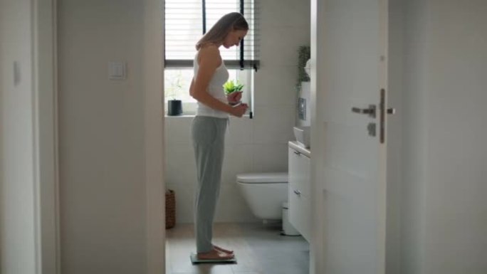 沮丧的白人妇女踩在浴室秤上。用8k的红氦相机拍摄。