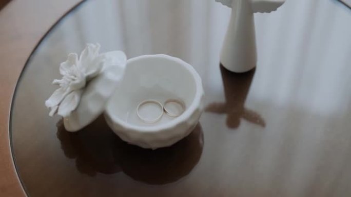 结婚戒指躺在白色圆形陶瓷盒中