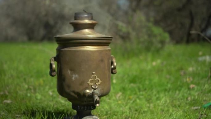 野餐时，一座古老的青铜茶炊站在草地上。